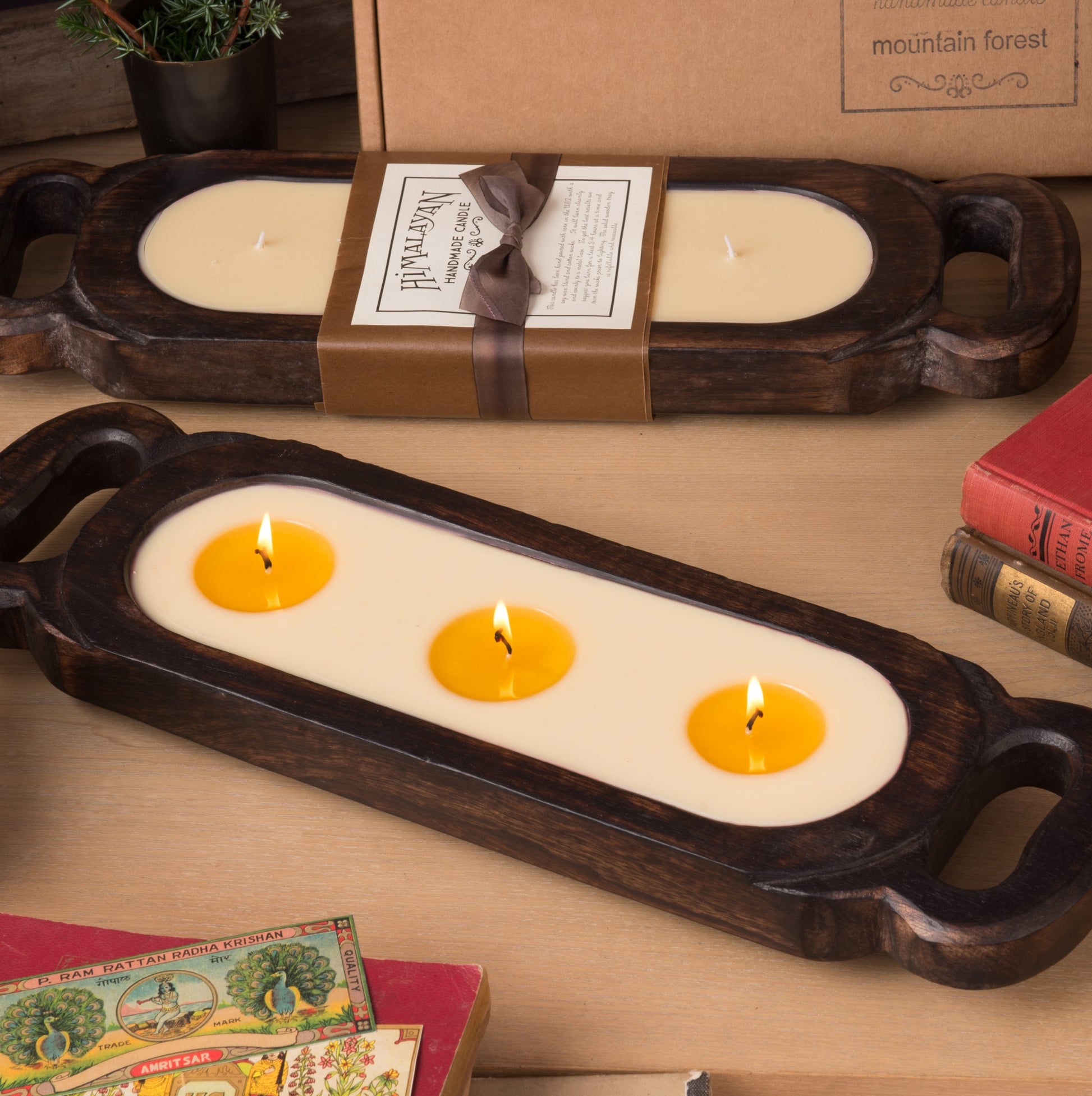 Wooden candle tray with 3 lit wicks on a wooden surface