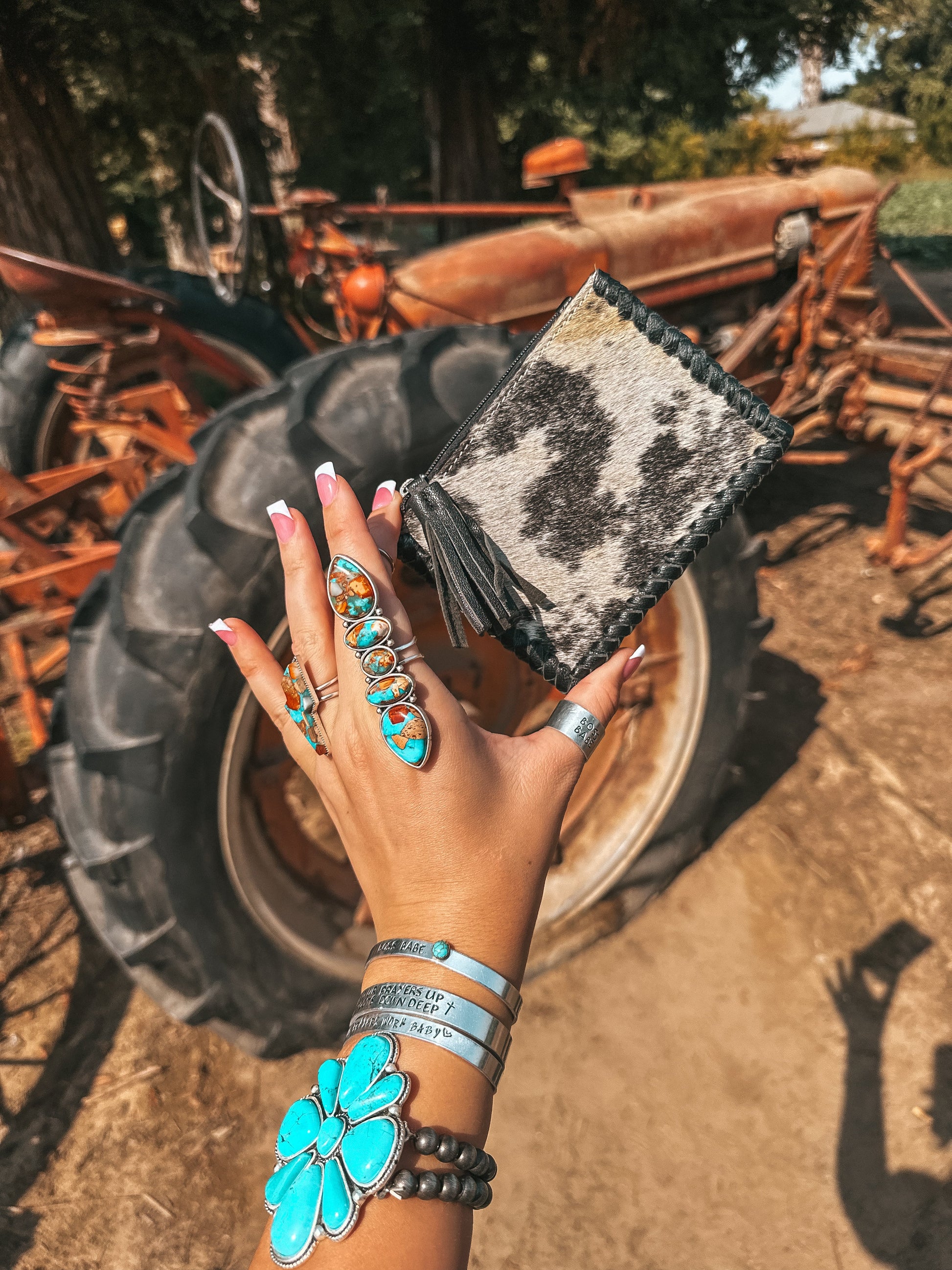 Hand holding a black cowhide wallet in front of a rustic background