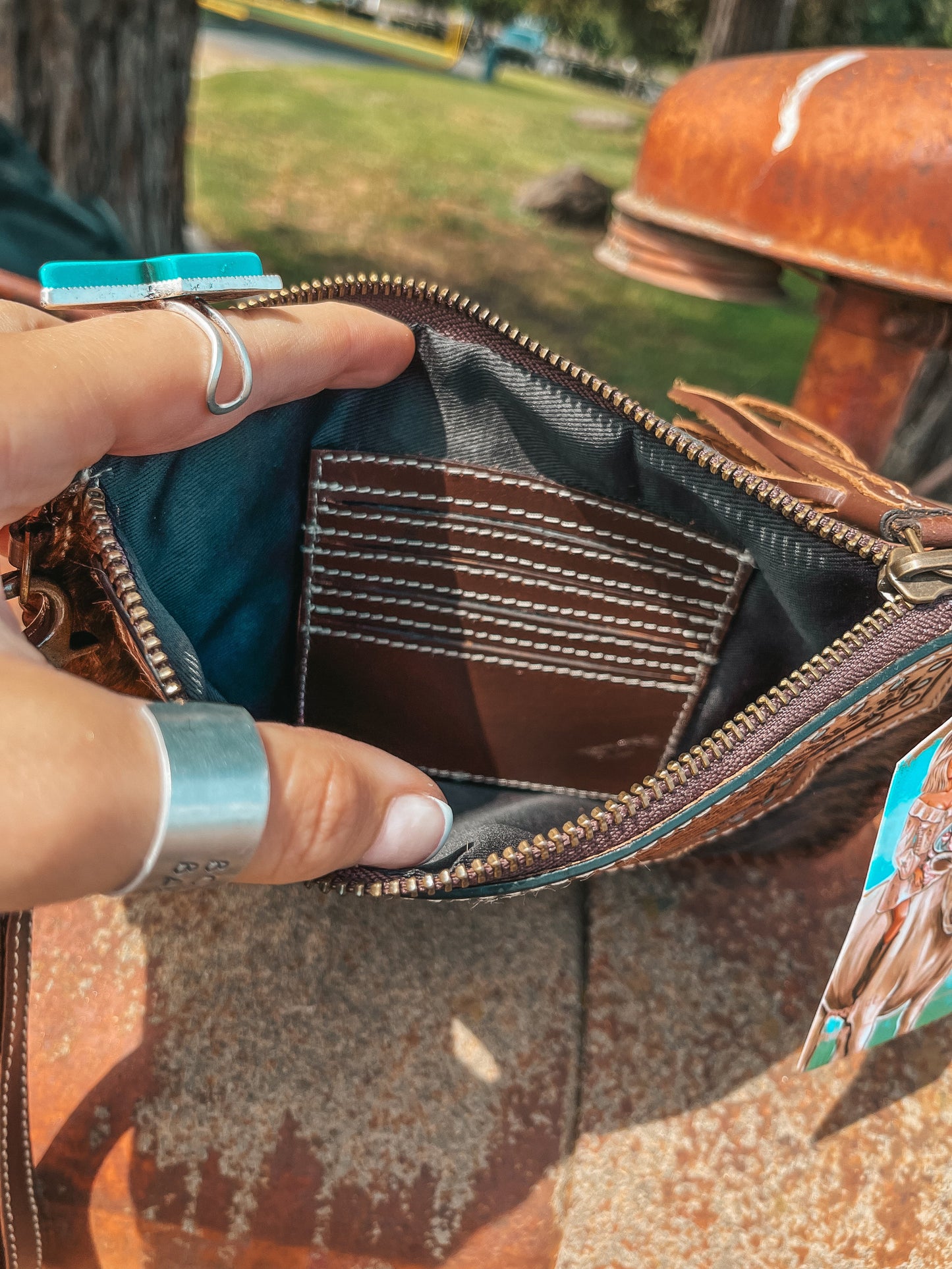 Close-up of a hand opening a brown leather bag with a patterned interior.