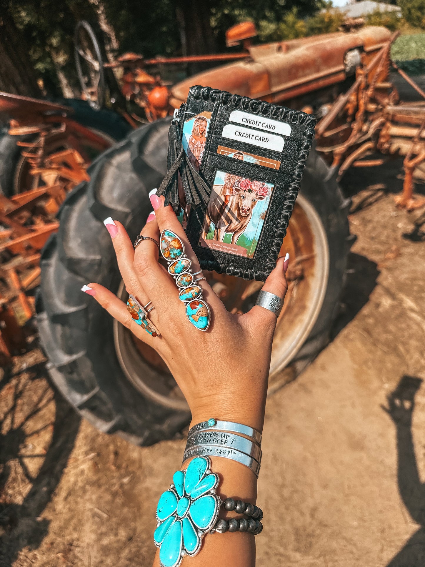 Hand holding a black leather wallet with card slots against a rustic background