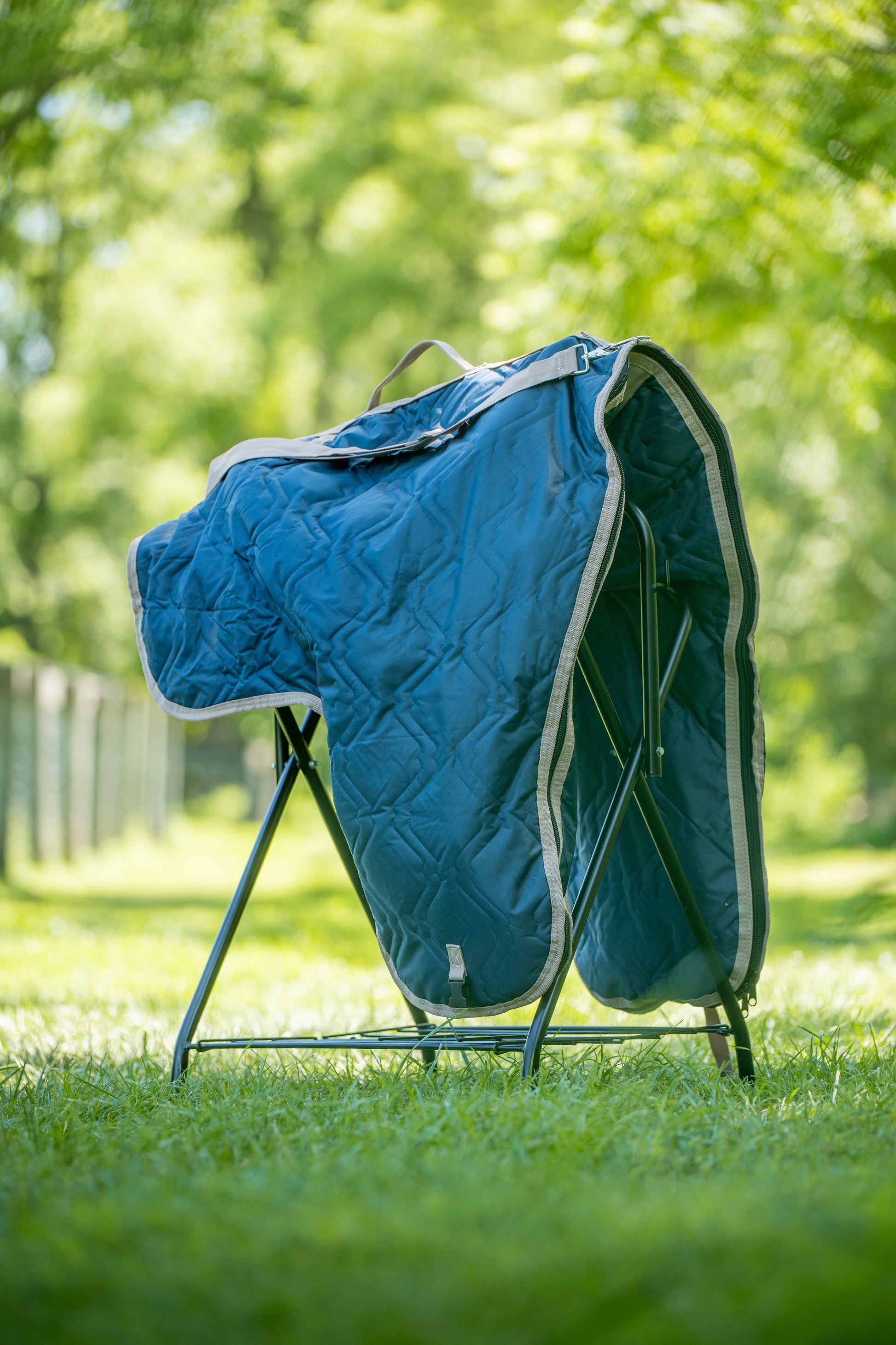 Blue saddle bag carrier on a stand in a grassy outdoor setting