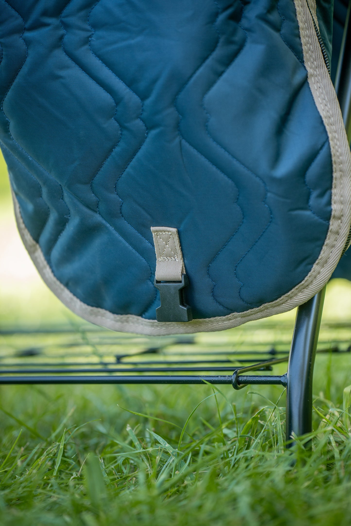 Blue quilted saddle bag carrier on a metal frame with grass in the background