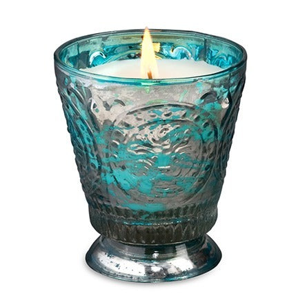 Blue glass candle holder with a lit candle on a white background