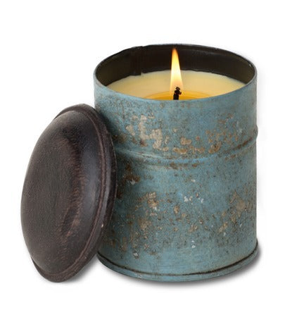 Candle in a rustic blue tin with a wooden lid on a white background