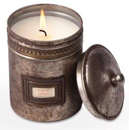Candle in a decorative metal container with a label on a white background