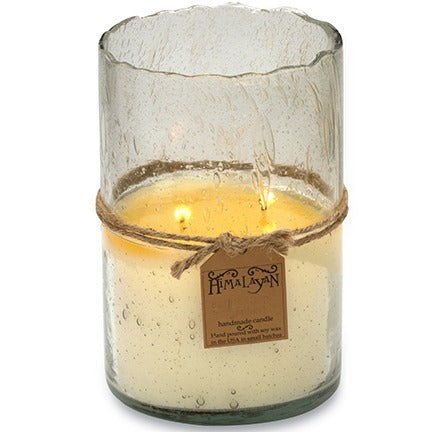 Candle in a textured glass holder with a decorative string holding a brand tag on a white background