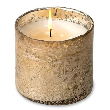 Candle in a textured metallic container on a white background