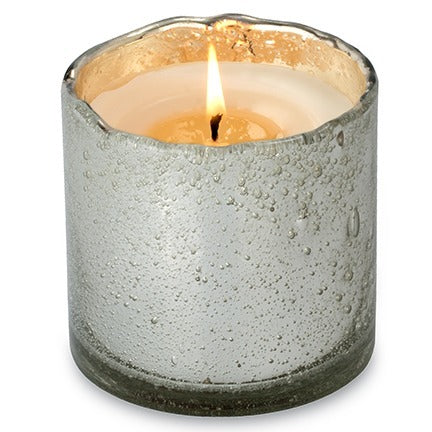 Candle in a textured concrete holder on a white background