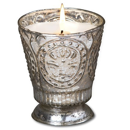 Decorative candle in a textured glass holder on a white background