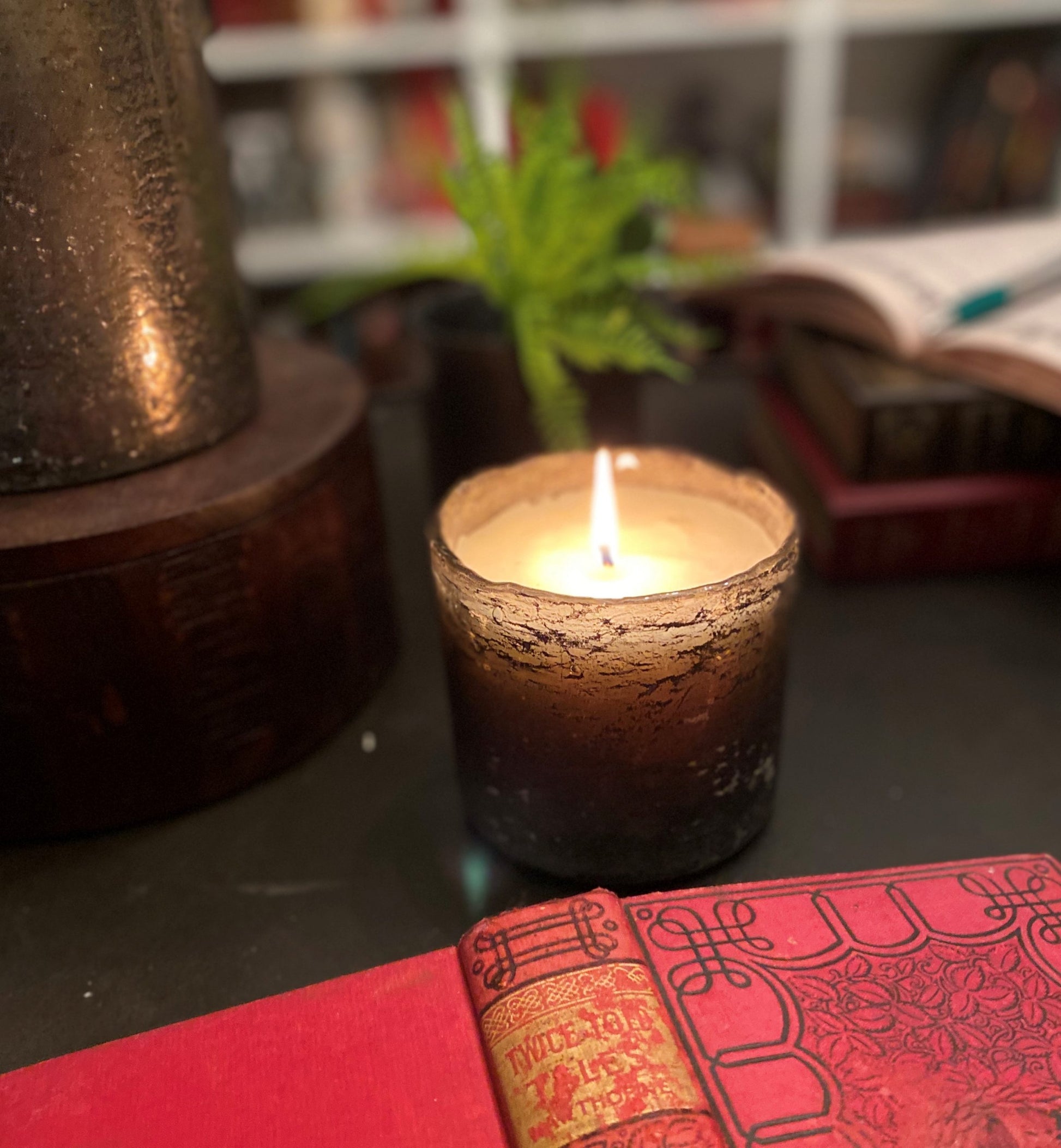 Candle in a textured holder on a table with a blurred background
